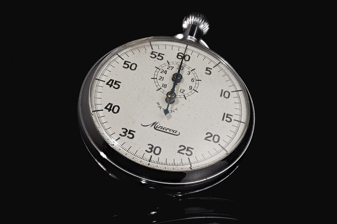 A vintage Minerva mechanical stopwatch with a white dial and a small 30-minute counter, photographed on a black background