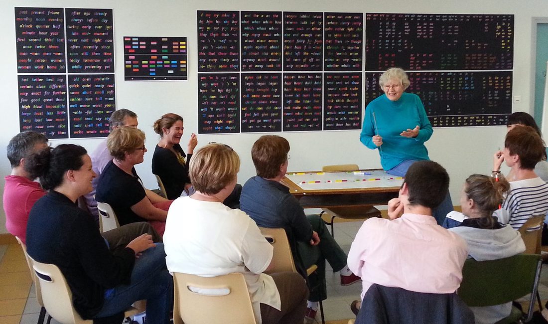 A language classroom with a teacher and visual aids on the wall