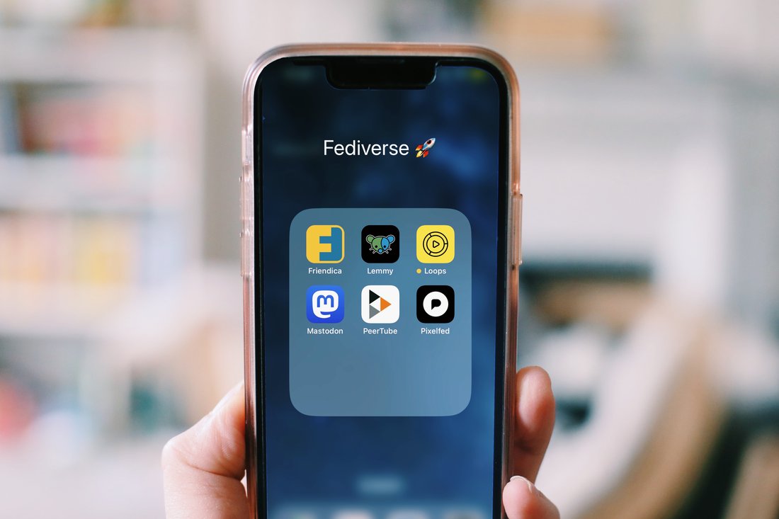 A hand holding a smartphone displaying a screen covered in app icons