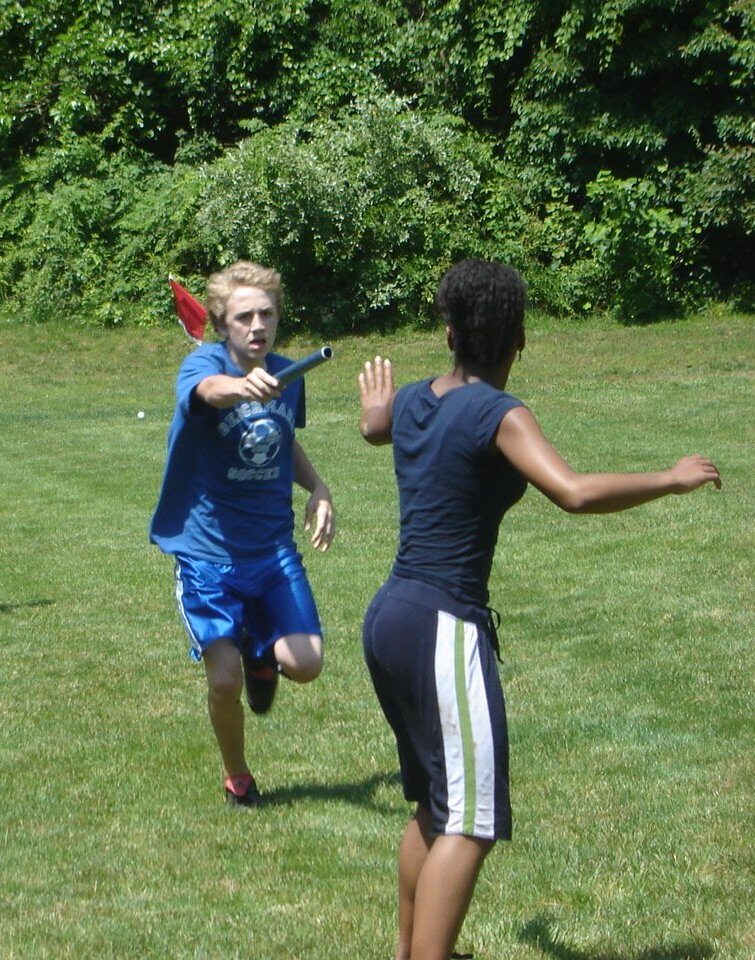 Two relay runners mid-handoff of a baton on a track